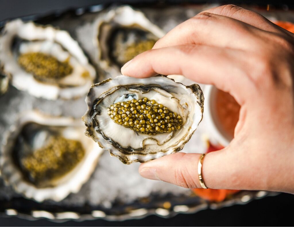 A hand holding caviar from Aqua Seafood & Caviar Restaurant, a restaurant in Resorts World.
