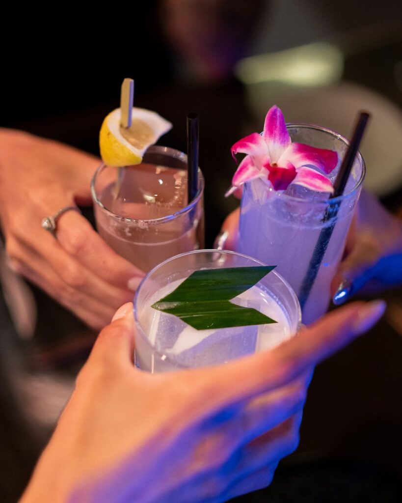 Three cocktails held in a toast at Aqua Seafood & Caviar Restaurant.