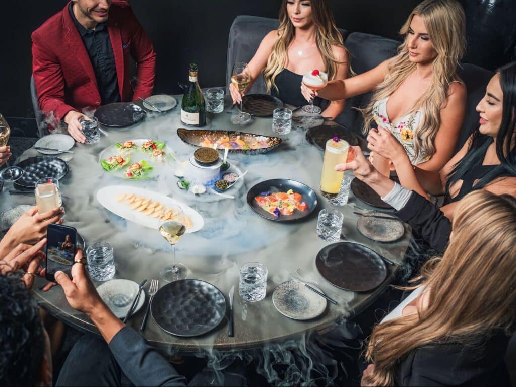 Friends sit around a table full of food at Aqua Seafood & Caviar Restaurant.